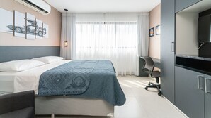 Habitación de hotel con cama, escritorio, silla, aire acondicionado y televisor.