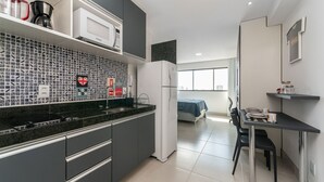 Una cocina moderna con un salpicadero blanco y negro, un refrigerador blanco y un comedor con mesa y sillas.
