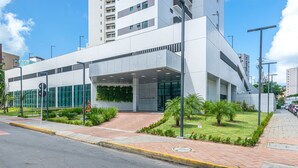 Un edificio moderno con fachada de vidrio, entrada cubierta y zona ajardinada.