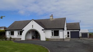 A white two-story house with a dark roof, a garage, and a driveway leading to the entrance. - Brookfield (Bude)
