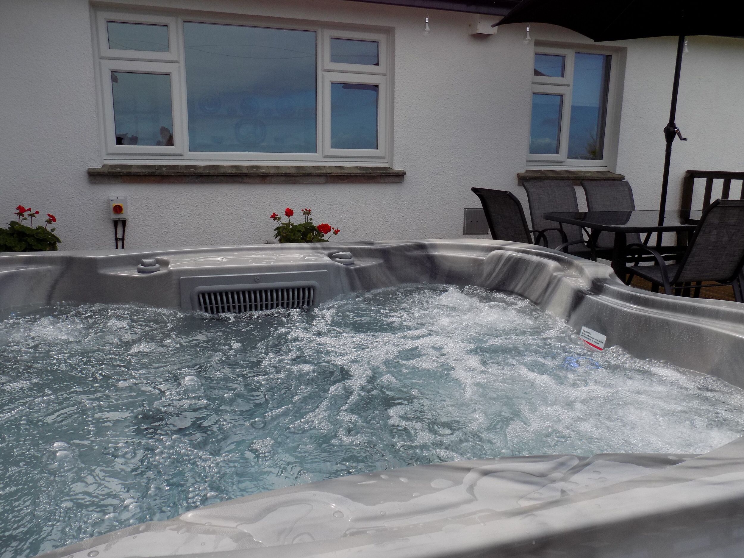 Un bain à remous rempli d’eau, une fenêtre et une chaise.