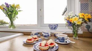 A breakfast table with tea cups, saucers, and a vase of flowers. - Brookfield (Bude)