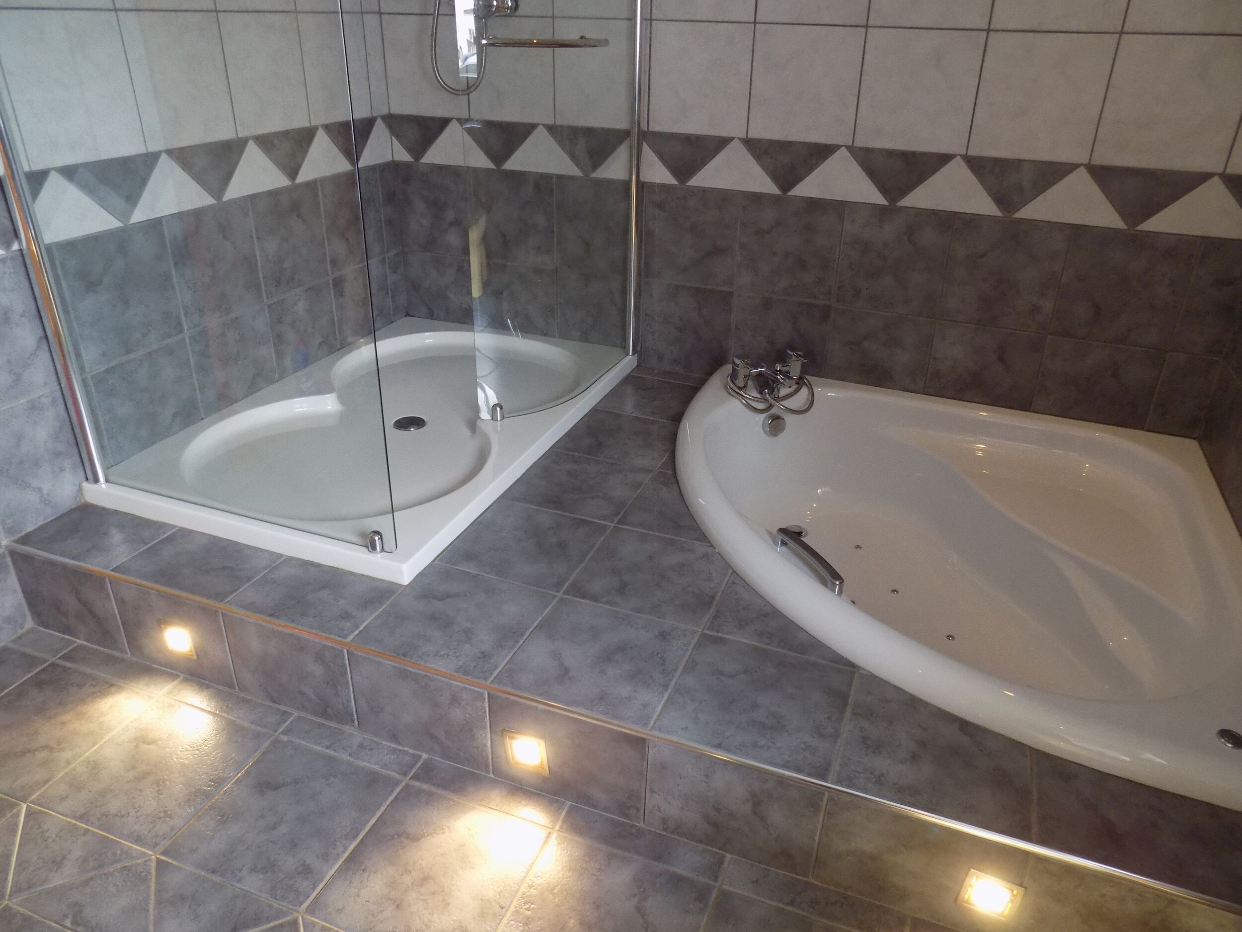 Une salle de bain dotée d’une douche à parois de verre, d’une baignoire sur pieds et d’un meuble-lavabo avec un miroir.