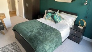 Ein Schlafzimmer mit Bett, Nachttisch, Kommode und Spiegel.