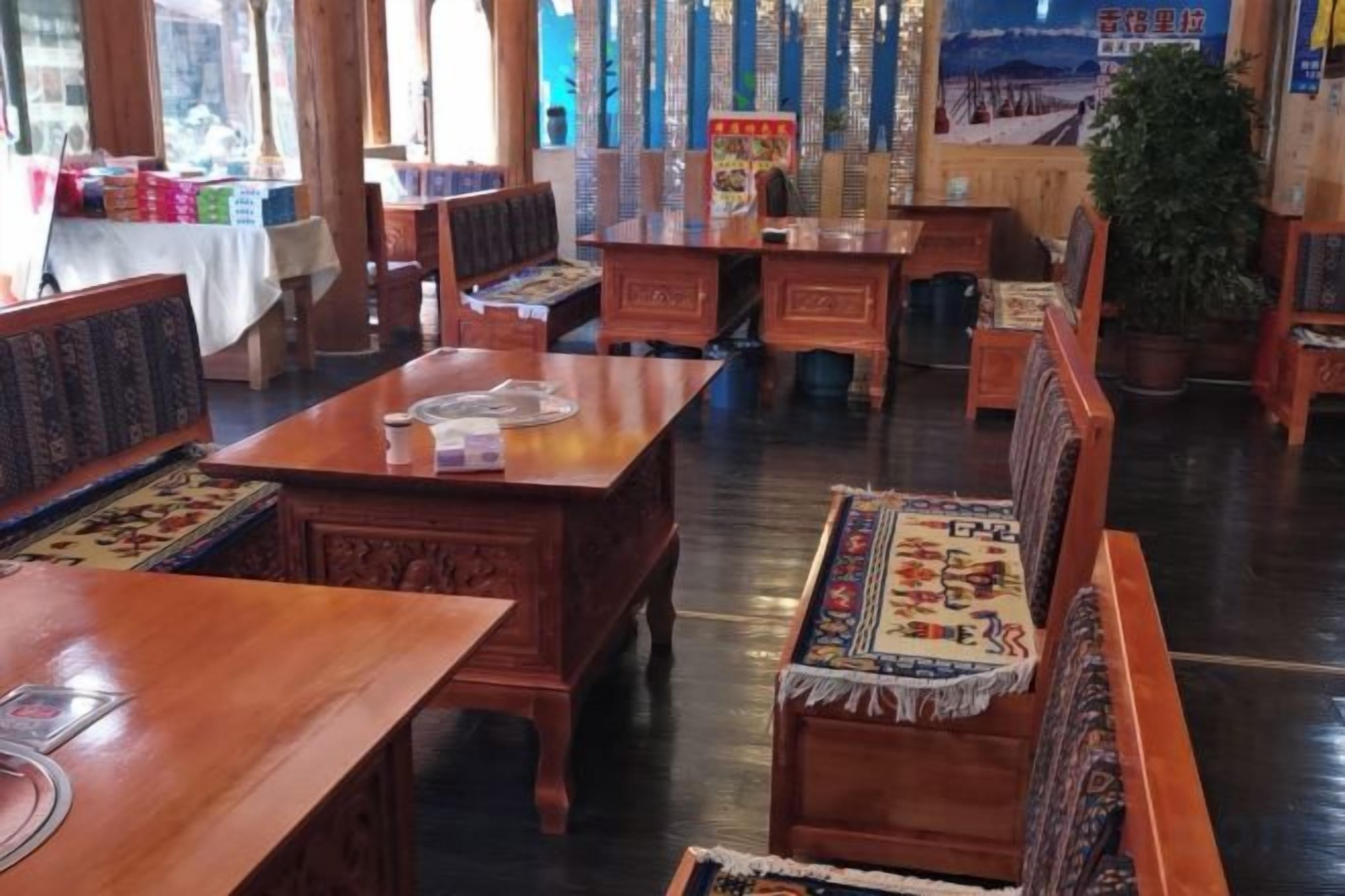 A traditional wooden dining area with tables and benches, some with patterned table runners.