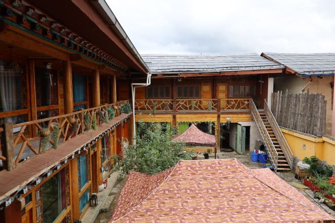 A traditional wooden building with a balcony, a covered patio, and a staircase.