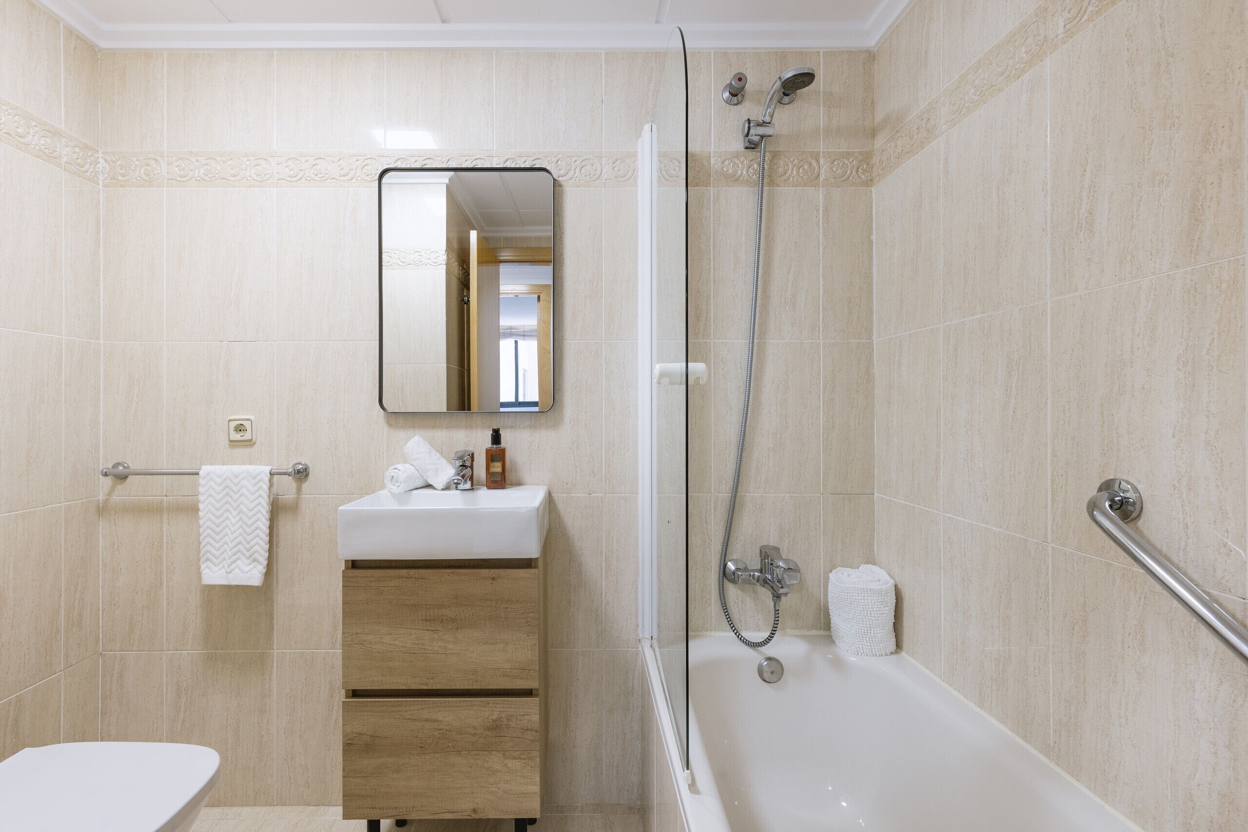 A bathroom with a bathtub, a sink with a mirror, and a towel rack.