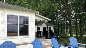 A building with a porch and three blue Adirondack chairs. - Hilltop Cottage (Argyle)