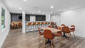 A modern conference room with a long table and chairs, a kitchen area, and a large window. - Travelodge by Wyndham Kissimmee/Orlando (Kissimmee)