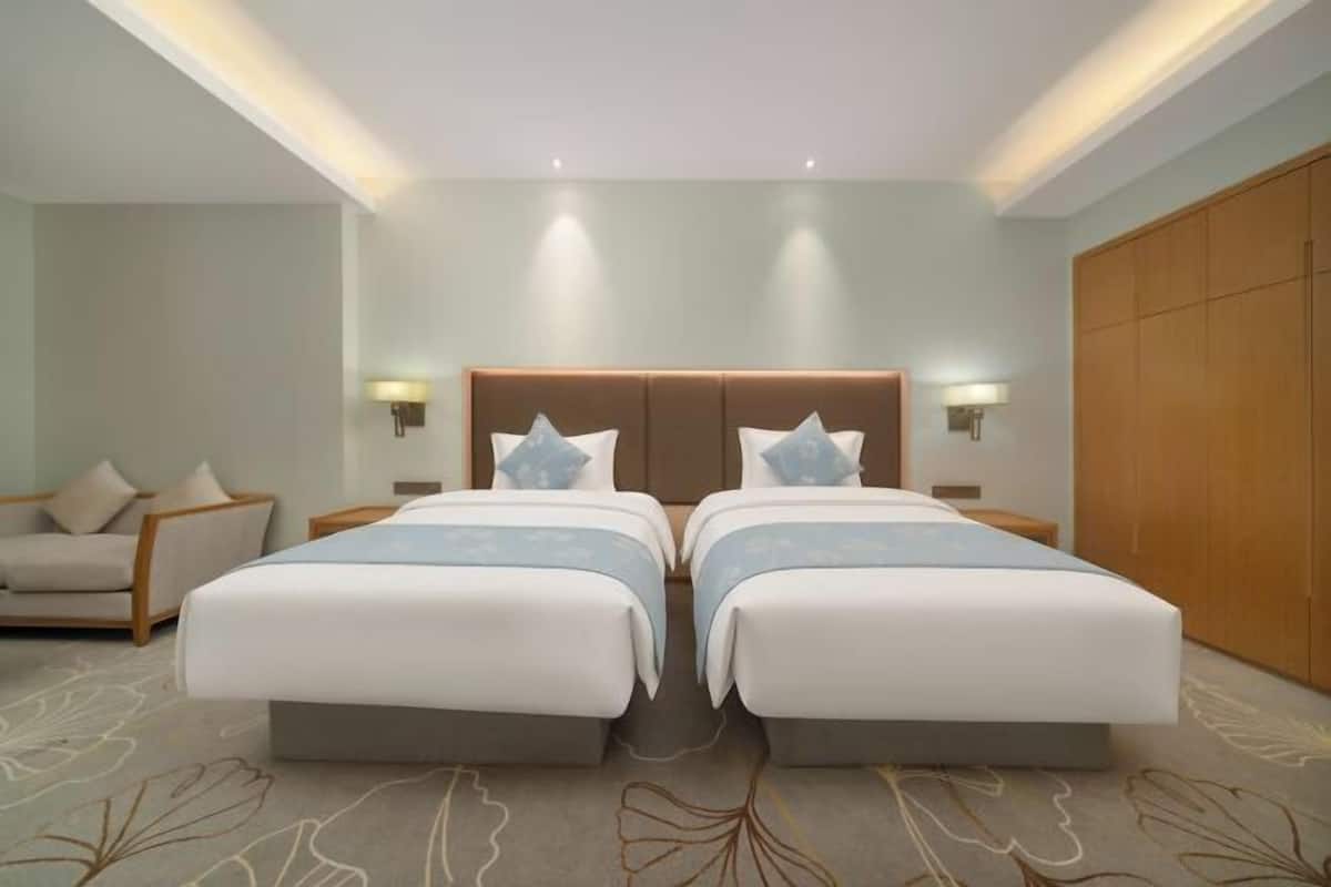 A hotel room with two beds, a sofa, and a wardrobe.