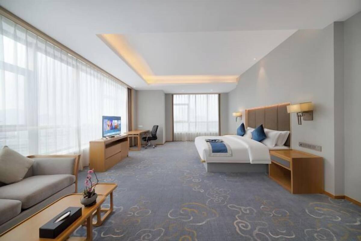 A hotel room with a bed, a desk, a television, a sofa, and a coffee table.