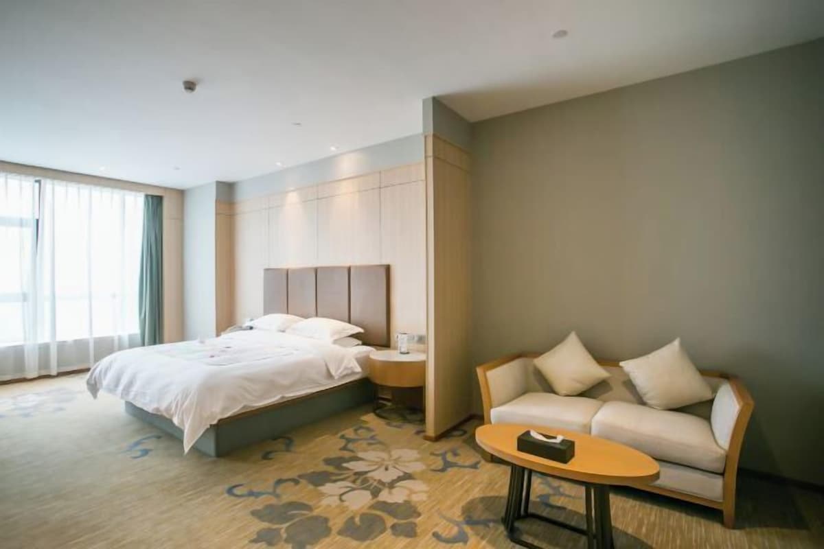 Una habitación de hotel con cama, sofá, una mesita y una mesilla de noche.