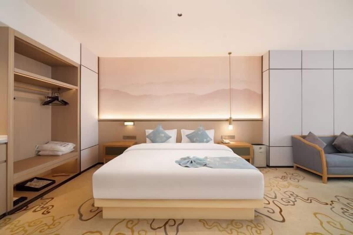 A hotel room with a bed, a wardrobe, a desk, and a chair.