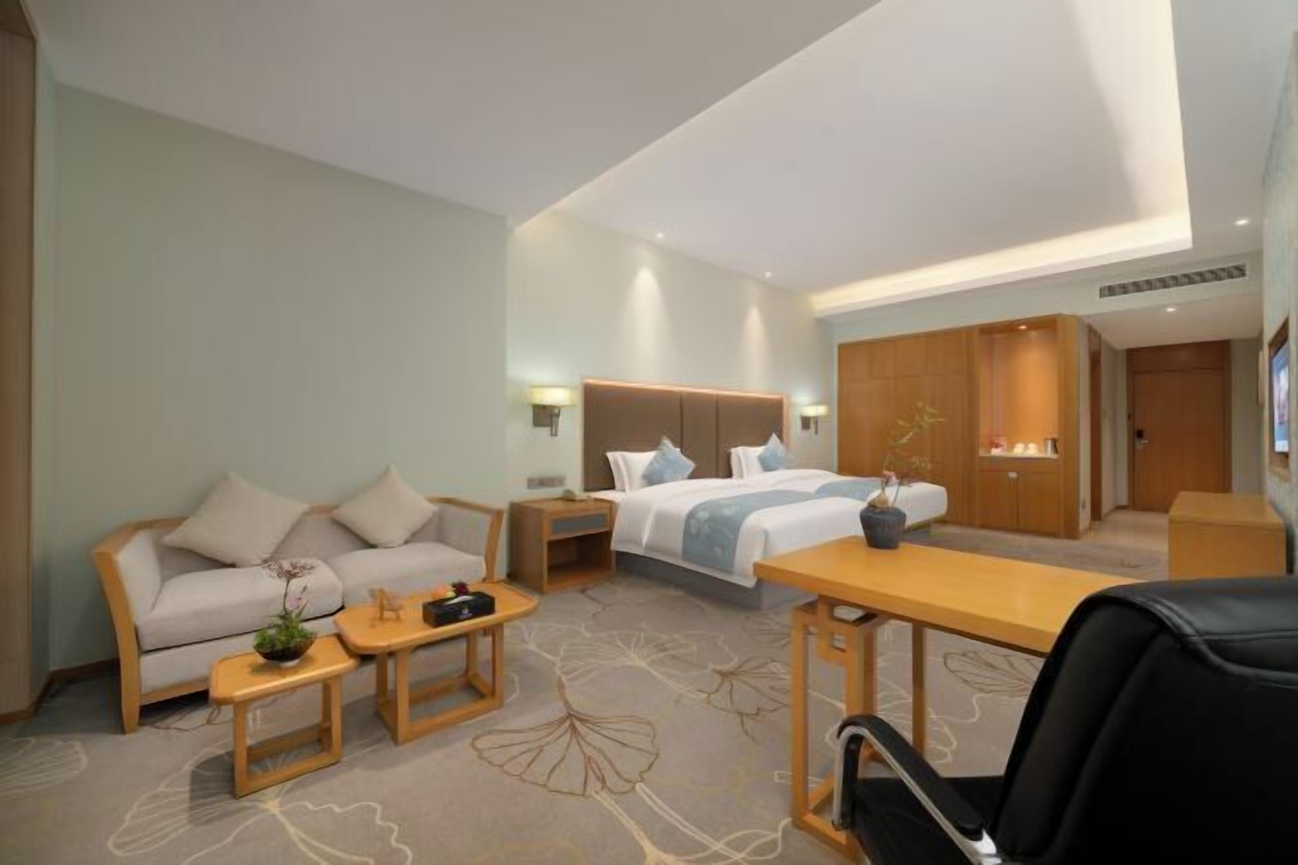 A hotel room with a bed, a sofa, a desk, and a chair.