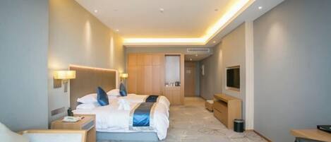 A modern hotel room with a large bed, bedside tables, a desk, and a television.