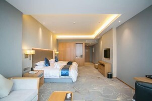 Una habitación de hotel moderna con una cama grande, mesitas de noche, un escritorio y una televisión.