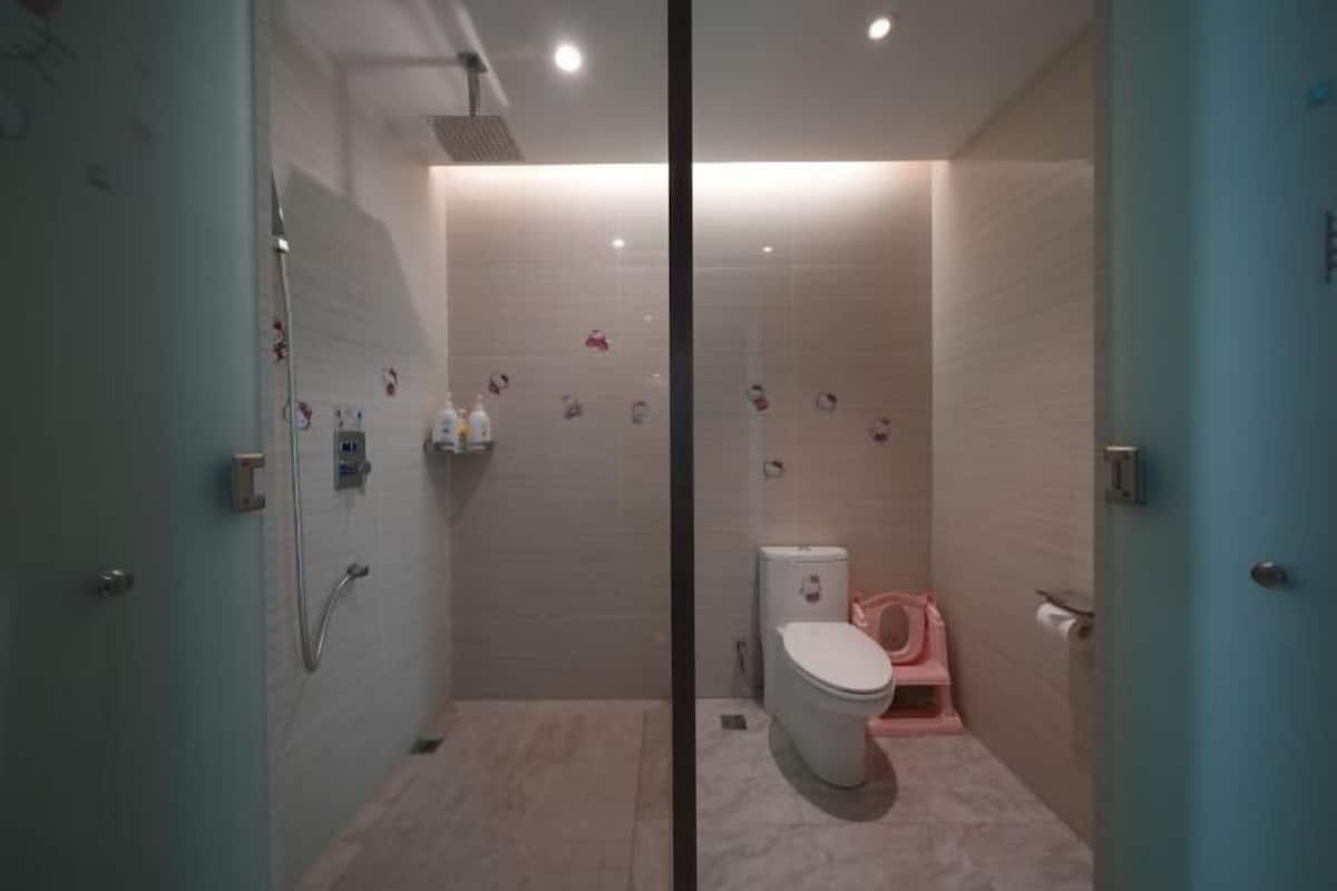 A modern bathroom with a shower, toilet, and a glass partition.