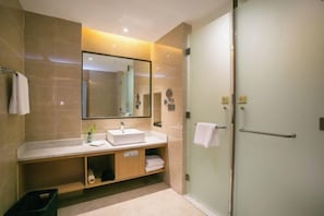 Un baño moderno con un espejo grande, un lavabo, una ducha y un perchero para toallas.