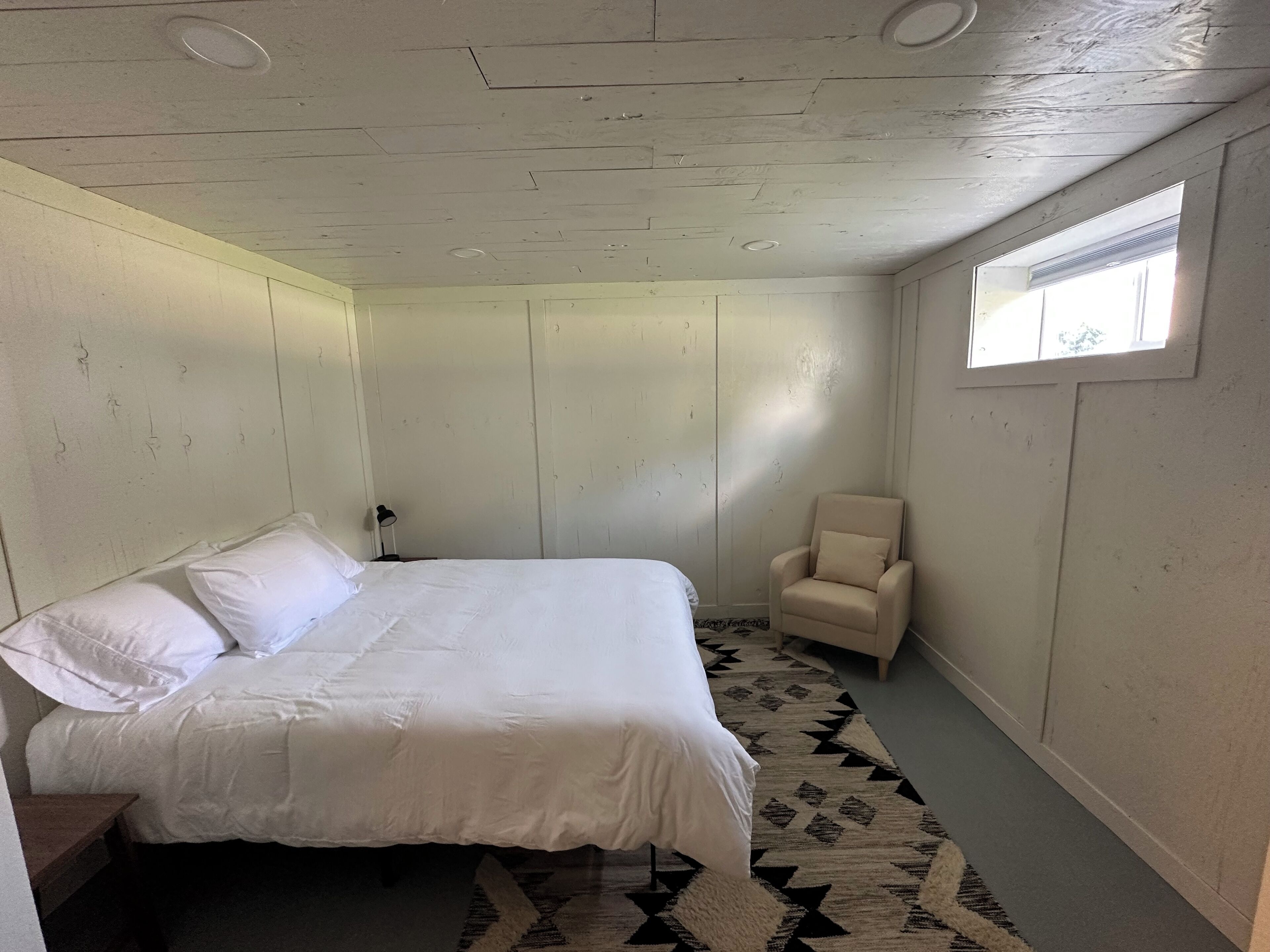 Una camera da letto con un letto, una sedia e una finestra.