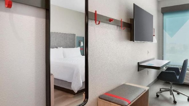 A hotel room with a bed, a desk, a chair, a TV mounted on the wall, and a mirror. - avid hotel FORT WORTH DOWNTOWN by IHG (Fort Worth)