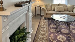 Un salon avec une cheminée, un canapé, une table basse et un tapis à motifs.