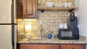Une cuisine avec des meubles en bois, un plan de travail en granit, un four à micro-ondes, une machine à café et une petite décoration représentant un vélo.