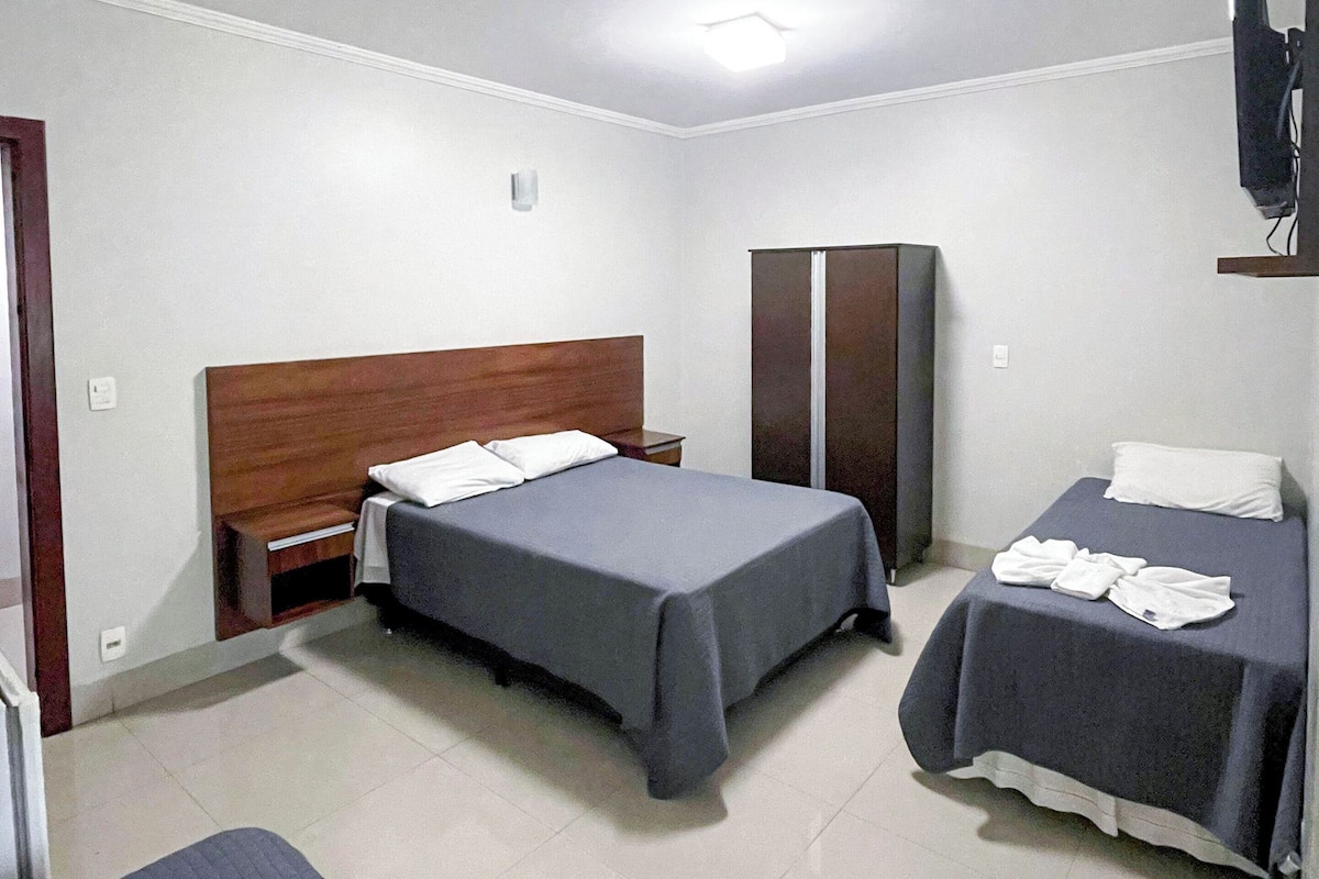 Una habitación de hotel con dos camas, un armario y un televisor.