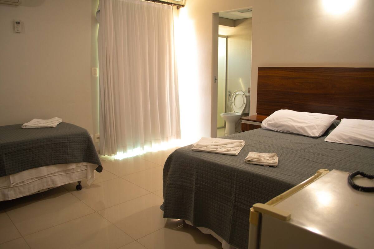 Habitación de hotel con dos camas, un baño y un espejo.