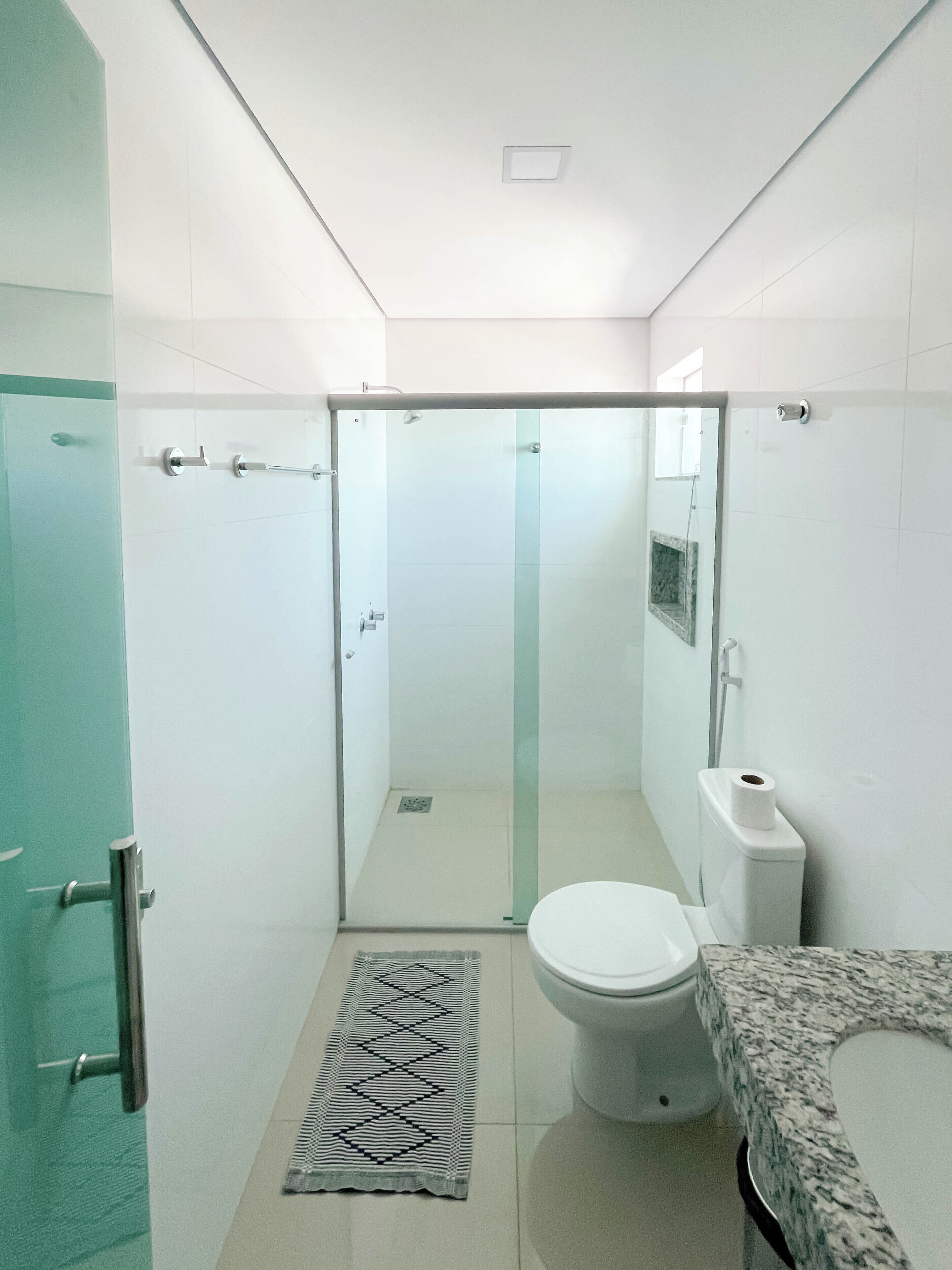 Une salle de bain moderne dotée d’une douche à parois de verre, de toilettes et d’un lavabo avec un plan de travail en marbre.