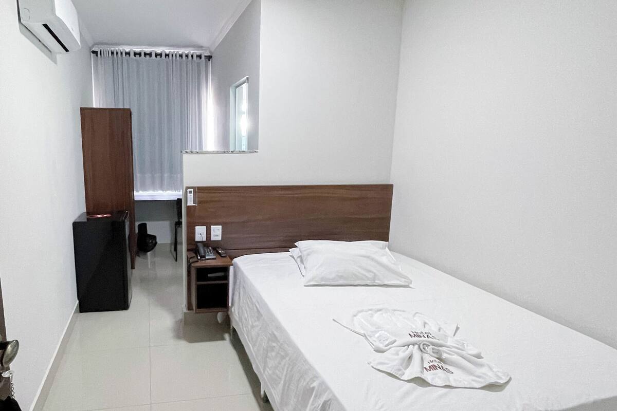 Habitación de hotel con una cama grande, una mesita de noche, un escritorio, una silla, un armario y un espejo.