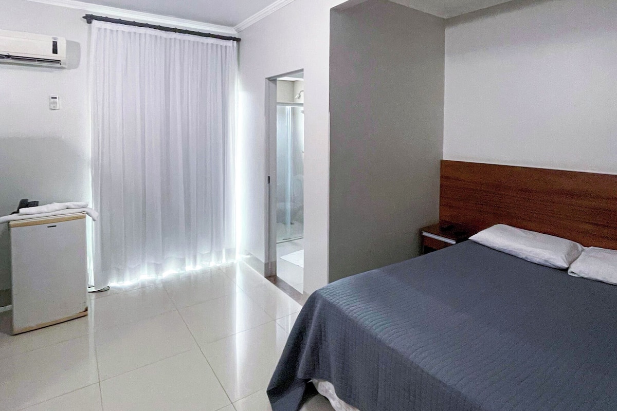 Una habitación de hotel con una cama, un escritorio pequeño y un espejo.