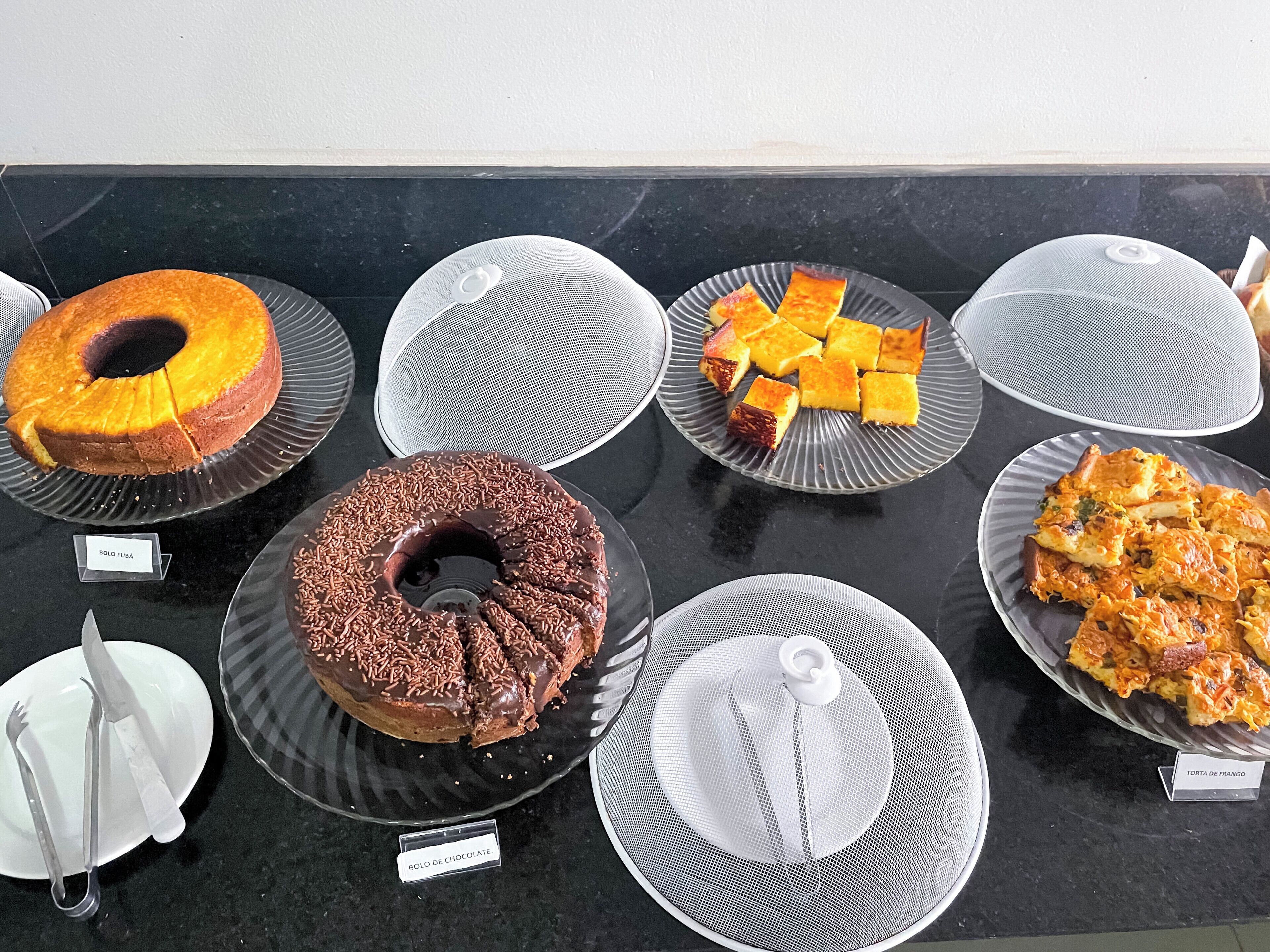 Variedad de postres a la vista, entre ellos un bizcocho de chocolate, un pastel de caramelo y una tarta de frutas.