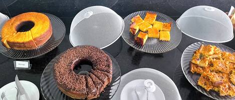 Variedad de postres a la vista, entre ellos un bizcocho de chocolate, un pastel de caramelo y una tarta de frutas.
