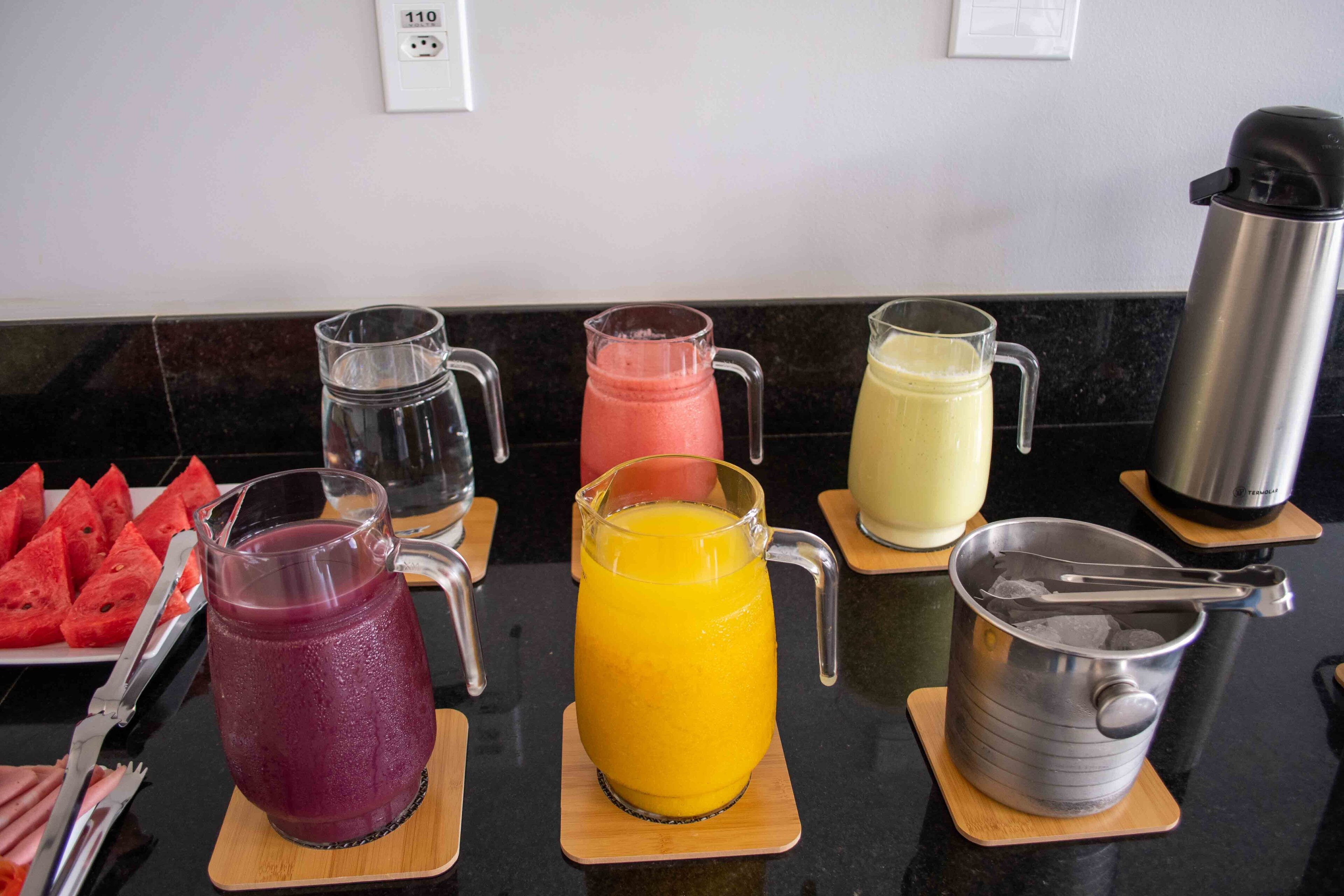 A breakfast buffet with various fruit juices and a watermelon tray.