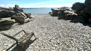 A rocky beach with large boulders and a clear view of the water.