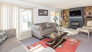 A living room with a sofa, a glass coffee table, a fireplace, and a TV.