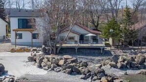 A modern house with a balcony, surrounded by rocks and trees.