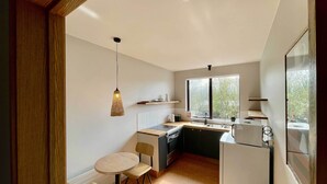 Una cocina compacta con comedor, lámpara colgante y ventana que proporciona luz natural.