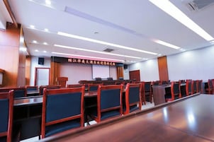 Un salón de conferencias con filas de sillas, una pantalla de proyecciones y un atril.
