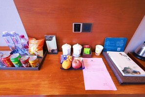 A hotel reception desk with a menu, a card reader, a tray with snacks, fruits, and beverages. - Huamei Hotel (Suijiang)