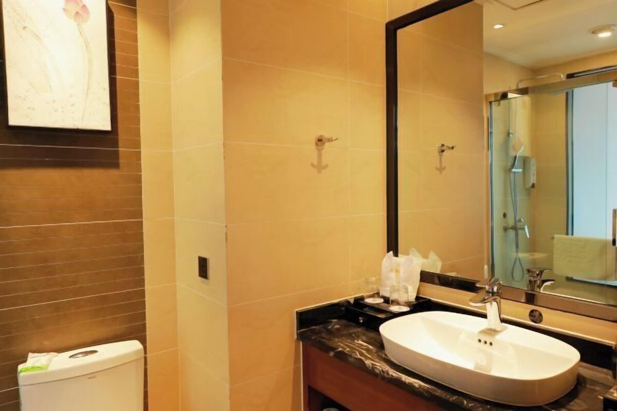 A bathroom with a white sink, a large mirror, and a toilet.