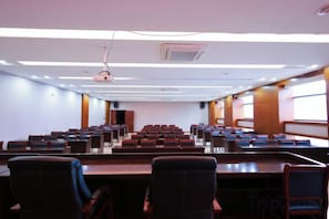 A conference room with rows of tables and chairs, a projector, and a large window. - Huamei Hotel (Suijiang)