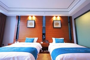 Habitación de hotel con dos camas, cabeceros de madera y obras de arte enmarcadas en las paredes.