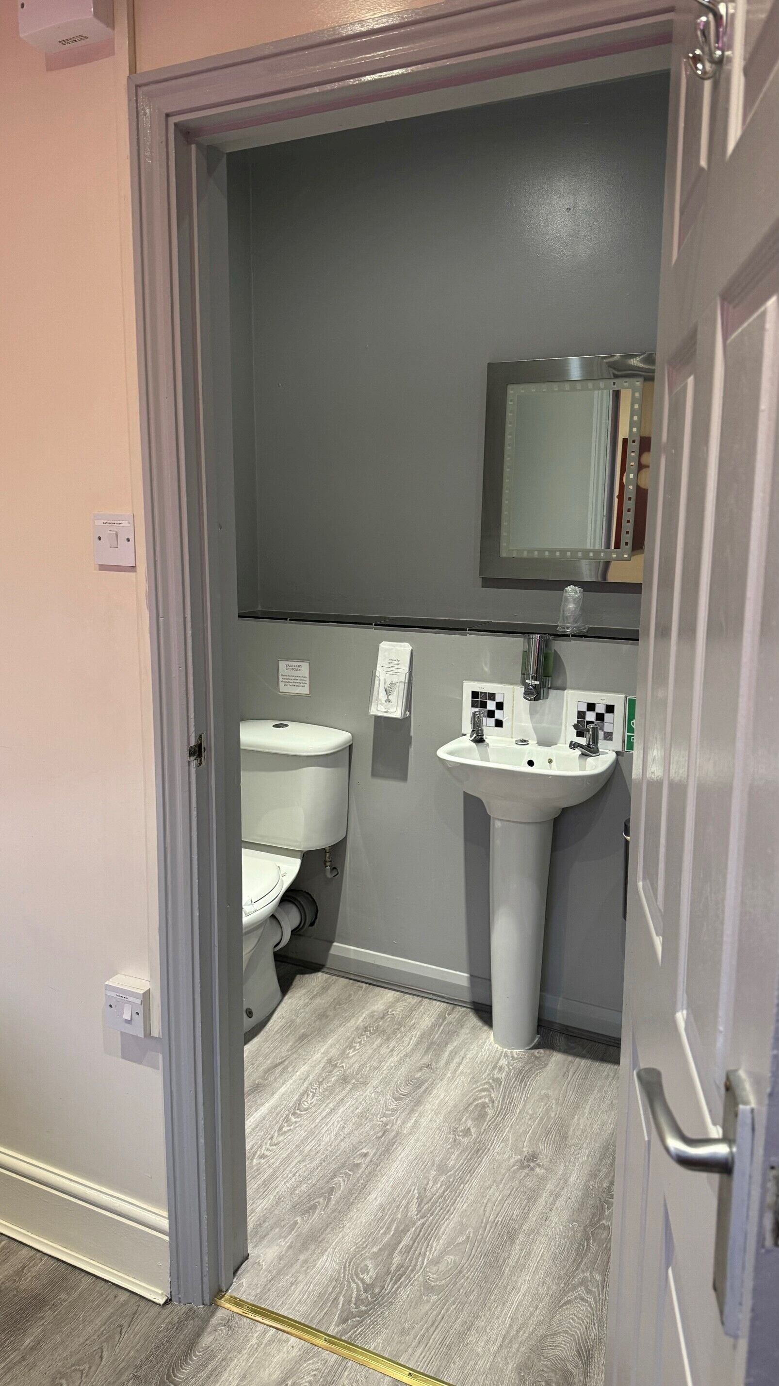 A bathroom with a toilet, sink, and mirror.