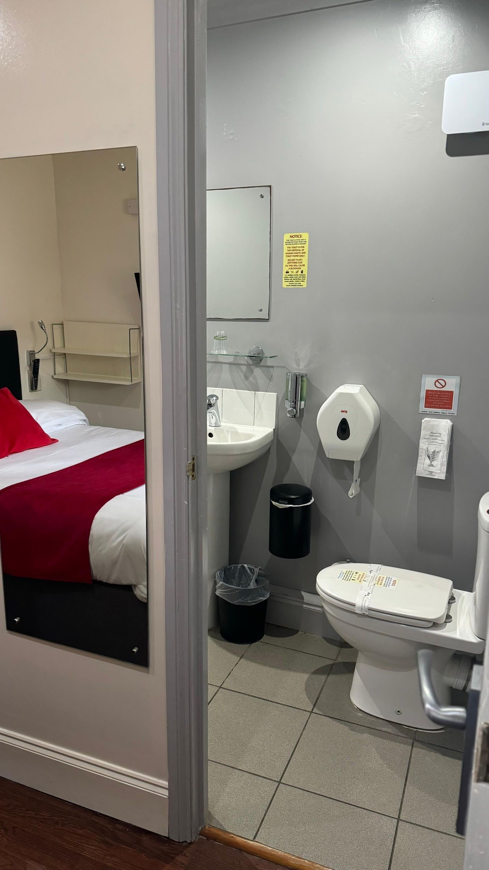 A hotel bathroom with a sink, toilet, and a mirror.