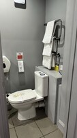 Um banheiro pequeno e compacto, com vaso sanitário, secador de mãos e dispensador de toalhas de papel.