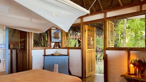 Ein Schlafzimmer mit Bett, Waschbecken und Blick ins Freie.