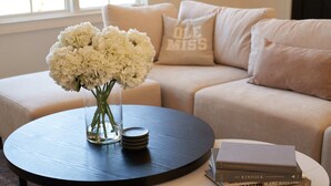 Een ronde tafel met een vaas witte bloemen en een stapel boeken.