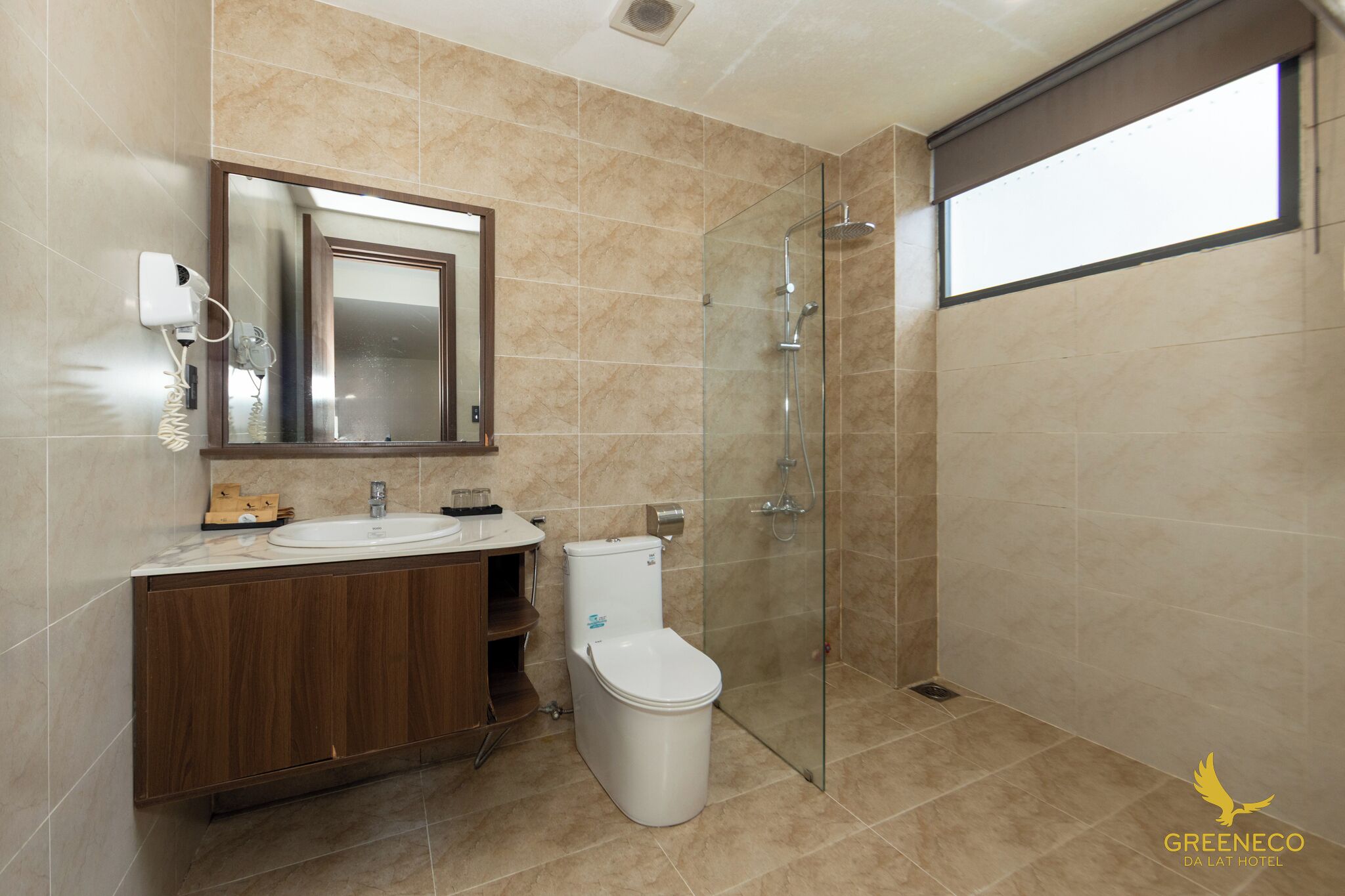 Une salle de bain moderne avec une douche à parois de verre, un lavabo avec un miroir au-dessus et des toilettes.