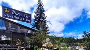 A restaurant with a pond and rocks, surrounded by greenery. - Green Eco Hotel Dalat (Xuan Huong - Da Lat)